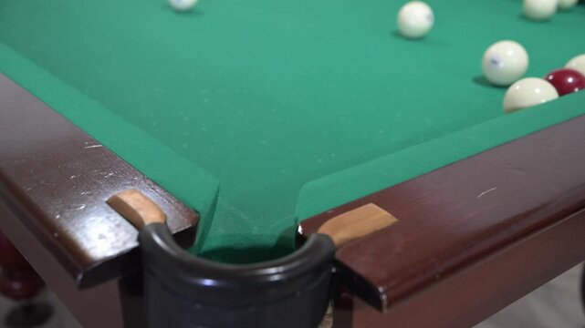 Hitting the ball with a cue and hitting the hole on the green background of the billiard table
