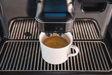 Automatic coffee machine brewing fresh espresso into white cup.