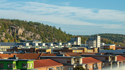 Scenic view of modern urban rooftops with forested hills in background.