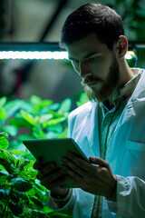 Scientist using tablet in greenhouse to monitor plants. Sustainable agriculture concept.