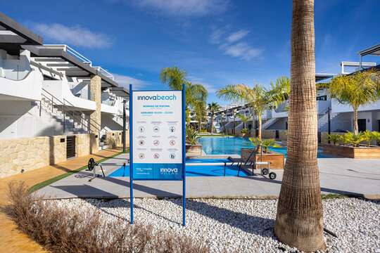 Innova Beach pool rules sign by tropical resort swimming area in Punta Prima, Alicante, Spain