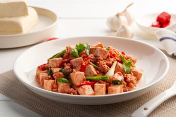 Stir fried Minced Pork with Deep Fried Tofu and red fermented bean curd in white plate.