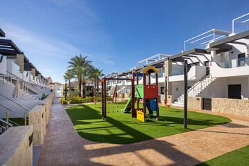 Gated community playground with palm trees at Innova Beach in Punta Prima, Spain