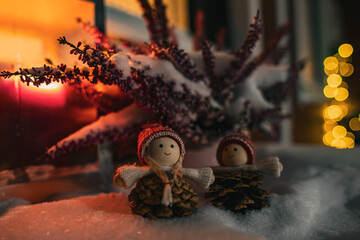 Cute handmade Christmas pine cone gnomes in the snow at night with candle light.