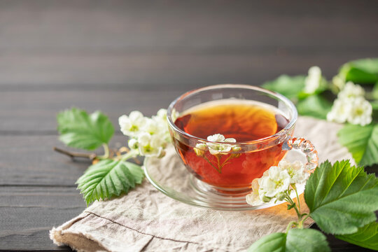Alternative herbal drink. Hawthorn spring floral tea with spring blooming branches  on wooden background