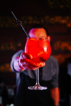 Bartender serves a colorful drink during a lively evening at a local bar