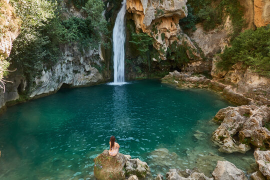 Young woman in bikini enjoying the crystal clear waters of La Calavera waterfall at Rio Borosa in Cazorla Natural Park Spain