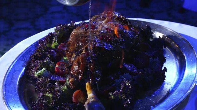A juicy baked piece of meat lies on a metal tray with vegetables.