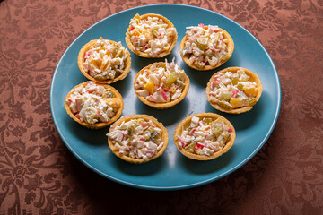 Shrimp and pineapple salad in tartlets on a plate on a brown tablecloth