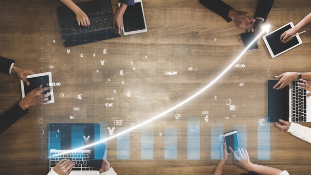 A top-down view of business professionals working together in an office, analyzing growth trends on digital devices while fostering a collaborative environment. Copula - Powered by Adobe