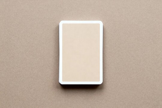 A flat lay image of a deck of cards (mockup) with a beige back and white border, placed centrally on a brown paper background, giving a simple and natural feel.