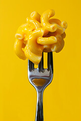 Creamy Macaroni on Fork Against Bright Yellow Background