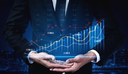 A businessman in a suit displays a digital graph with upward trends in a city night backdrop, symbolizing investment and financial analysis for businesses. Scalp