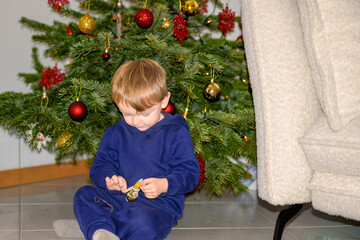Toddler Unwrapping Treat By Christmas Tree