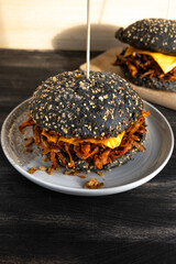 Vegan pulled mushroom burger with black bun on dark background