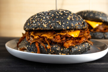 Vegan pulled mushroom burger with black bun on dark background