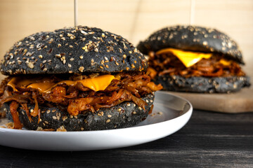 Vegan pulled mushroom burger with black bun on dark background