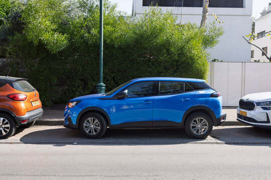 Side view of a blue Peugeot 2008 compact suv parked on a city street, Herzliya Pituach, Israel, 22 November, 2025