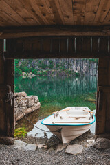 Boat sits by the water in a small cove in Norway surrounded by cliffs and green trees during the day