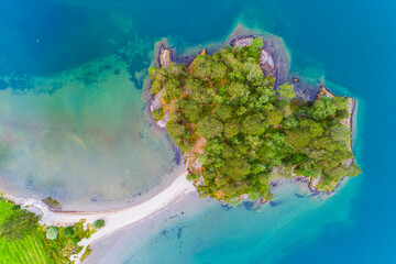 View of an island and beach at Lake Oppstrynsvattnet in Norway on a sunny day with clear water and greenery