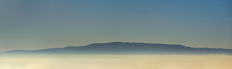 Panoramic view to inversion fog with hill Klet above. South Czech republic famous mountain