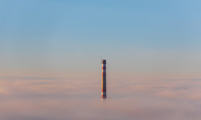 Chimney peeks out of the inversion fog above city Ceske Budejovice. Czech republic