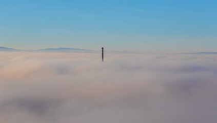 Chimney peeks out of the inversion fog above city Ceske Budejovice. Czech republic
