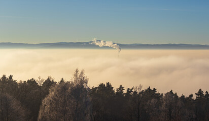 Chimney peeks out of the inversion fog above city Ceske Budejovice. Czech republic