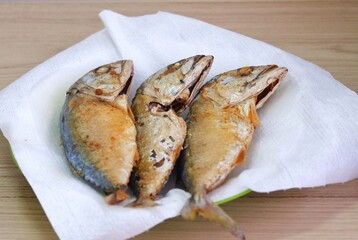 A group of Fried mackerels in a white plate on a wooden table background, Asian food 