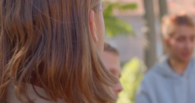 In a serene park, a man and woman share a heartfelt conversation. Nearby, two joyful young women are present, while one displays deep emotions