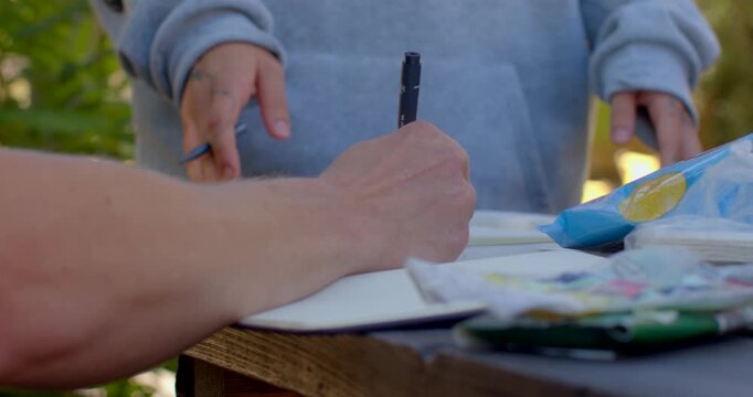 This video features individuals writing at a table a man and woman collaborate, while others reflect and create, showcasing creativity and introspection