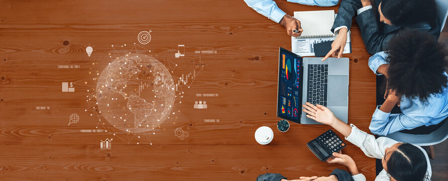 A diverse group of professionals collaborates around a table, utilizing a laptop and digital tools to analyze data and develop strategies for global business growth. Trope - Powered by Adobe