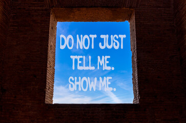 Tell or show symbol. Concept words Do not just tell me, show me on beautiful window in ancient brick wall. Beautiful blue sky background. Business tell or show concept. Copy space.