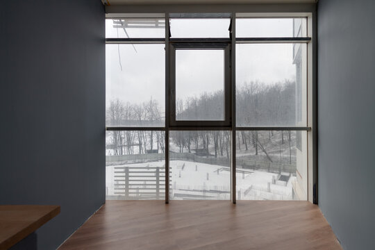 Empty apartment interior with large panoramic window overlooking winter construction site