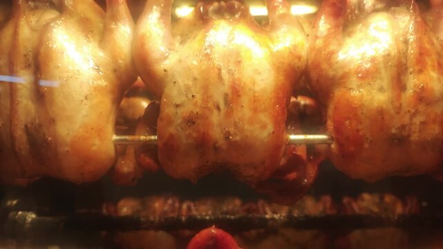 Chickens roasting. Close up whole chickens roasting on rotating rotisserie inside industrial oven. Golden skin glistens under heat. Food production roasting process and commercial kitchen operations.