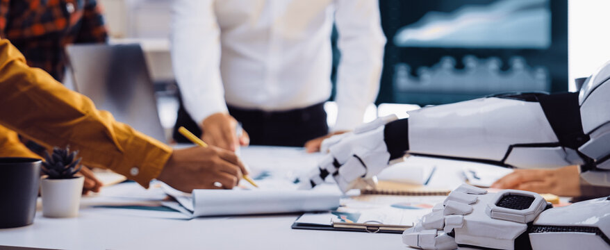 A dynamic office scene showcasing collaboration between humans and a robot, illustrating teamwork in data analysis and innovative business strategies.Noogenesis - Powered by Adobe