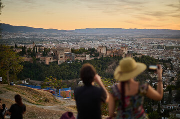 Fototapeta premium Tourists and locals watching the sunset over the Alhambra and Albaicin from San Miguel Alto