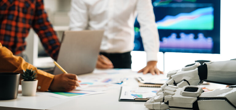 A dynamic modern office scene highlighting collaboration between human workers and a robot. Data analysis and teamwork are emphasized through visuals and technology.Noogenesis - Powered by Adobe
