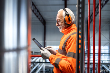 Senior worker using tablet in industrial factory