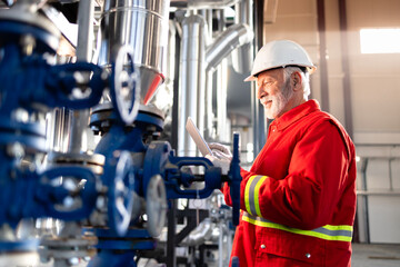 Senior engineer working on industrial pipeline with tablet