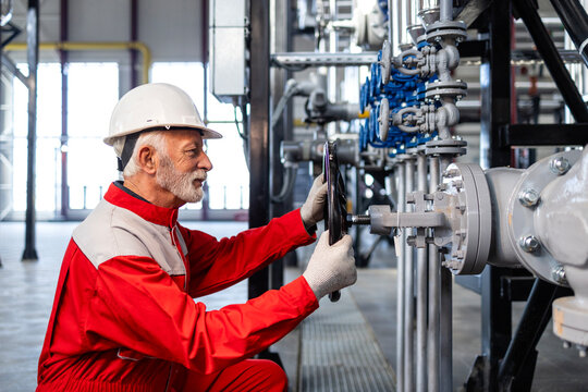 Senior industrial worker adjusting valve in processing plant