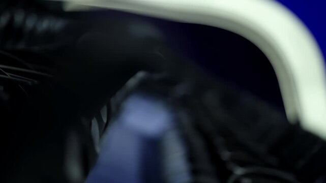 Shallow depth of field along rows of empty auditorium seats, dark armrests and blue aisle accentuating repetitive geometry and sleek modern design in a quiet, dim interior.