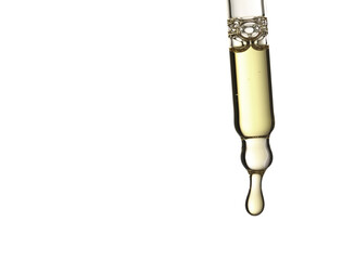 Studio shot of a glass pipette filled with clear cosmetic oil with a single drop forming at the tip, isolated on a white background
