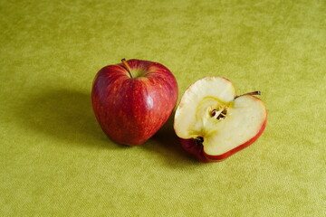 Closeup of whole and a half Starkrimson red apples on green background with copy space