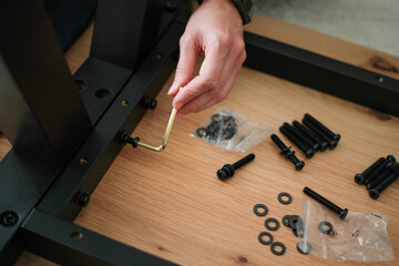 Woman assembling furniture at home. Female hands tightening screws into new wooden coffee table.