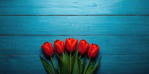 Blue wooden background with scattered red tulips, used for editorial headers or design elements, World Flower Day