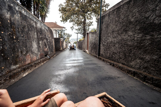 Scenic view of a child enjoying a thrilling toboggan ride downhill on a wicker sled in Funchal, Madeira, Portugal, with the famous Carreiros do Monte