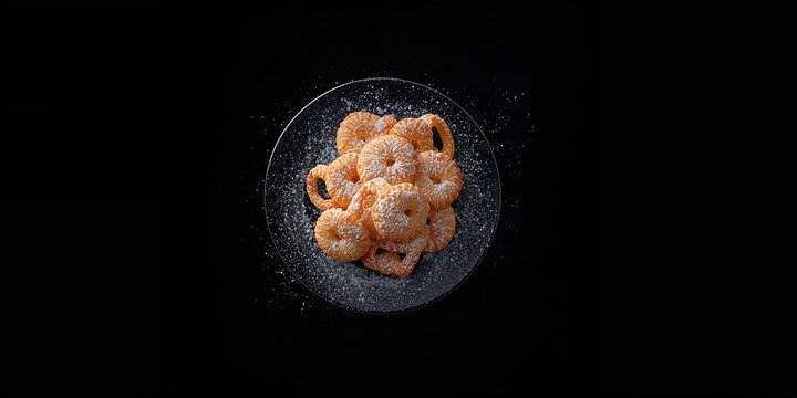 Oreillettes, a traditional French treat with powdered sugar topping, set against a black background, World Food Day