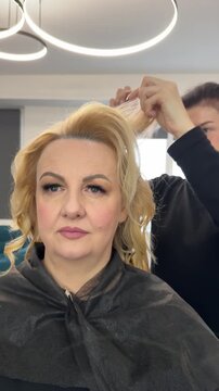 A skilled and professional stylist is meticulously working on a clients hair in a stylish and chic salon environment