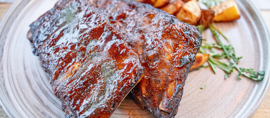 Grilled barbecue ribs with roasted potatoes served on rustic plate